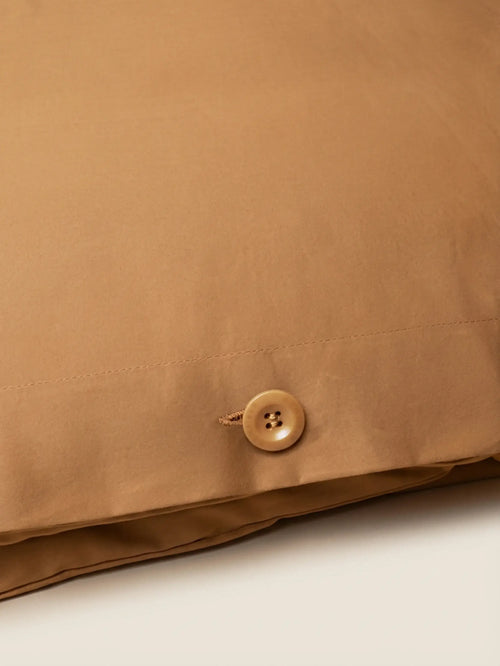 Close-up of Sateen Bedding Set - Desert Sand showing smooth fabric and a decorative button detail.